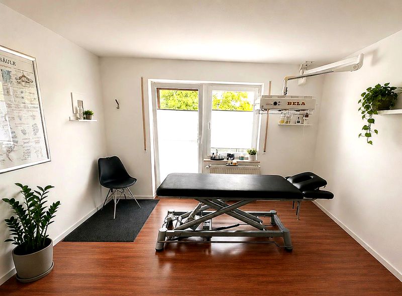 Behandlungszimmer mit höhenverstellbarem Therapietisch, Infrarot-Wärmestrahler und Pflanzen